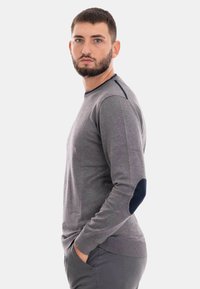 Maglione grigio a maniche lunghe con toppe blu sui gomiti e scollatura a girocollo. Realizzato in tessuto morbido, presenta un orlo e polsini a coste.