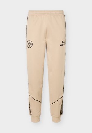 Pantalon jogger beige avec logos noirs BVB 09 et Puma King, bandes latérales à motifs, taille élastique et poignets.