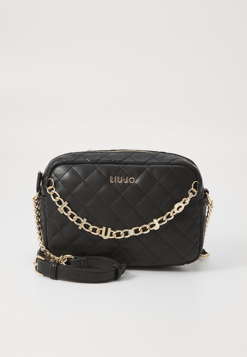 Bolso bandolera de cuero sintético negro acolchado con detalle de cadena dorada. Cuenta con cierre de cremallera y una correa ajustable. Logo de la marca embellecido en la parte frontal.