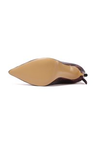 Zapato de tacón alto con punta afilada en burdeos, fabricado en cuero con textura suave. Presenta una suela de goma beige y un sutil acento de logo.