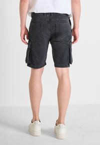 Shorts cargo in denim nero con due tasche laterali e tasche posteriori, caratterizzati da un orlo sfilacciato e una vestibilità ampia.