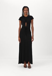 Abito maxi nero realizzato in tessuto morbido, con un design annodato e un'apertura a forma di chiave sul petto e maniche corte a campana.