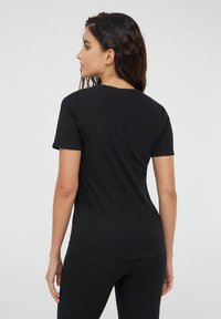 Czarna, krótko rękawowa koszulka z miękkiego materiału, dopasowany krój z klasycznym okrągłym dekoltem, gładka faktura, idealna do codziennego noszenia.