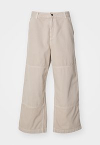 Pantalones de pierna ancha beige, confeccionados en algodón texturizado, con cierre de botón, bolsillos delanteros y detalles en paneles contrastantes.