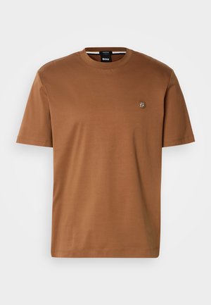 Braunes T-Shirt mit kurzen Ärmeln aus weichem Stoff, mit einem Rundhalsausschnitt und einem kleinen Logopatch auf der Brust. Glatte Textur.