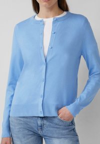 Lichtblauwe gebreide cardigan met een ronde hals, knoopsluiting en geribde manchetten en zoom. Draag het over een witte top, gecombineerd met lichte denim.