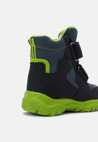Stivaletto per bambini blu scuro con dettagli verde lime, superiore in tessuto e strap in velcro. Presenta una suola verde testurizzata e un tallone rinforzato.
