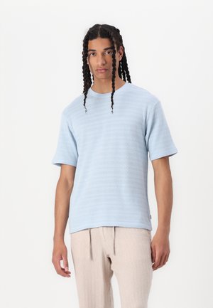 Lichtblauwe T-shirt met korte mouwen, van een gestructureerde stof, met een ronde hals en een rechte zoom, gecombineerd met beige, losvallende broeken.