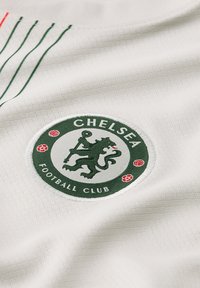 Weißer Stoff mit strukturiertem Gewebe zeigt ein grünes, kreisförmiges Logo des Chelsea Football Clubs, das einen Löwen und florale Akzente darstellt, alles gestickt.