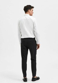 Hvitt langermet skjorte med en skarp krage; svarte skreddersydde bukser; elegante svarte sko; glatte teksturer; minimalistisk design.