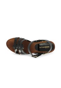 Sandalia de cuero negro con plantilla de madera, que presenta múltiples correas y un hebilla. Textura suave, diseño de punta abierta y suela plana.
