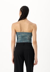 Denim топ bez naramenica s uskim dizajnom, s svijetloplavim pranjem, stražnjim šavovima i glatkom teksturom, uparen s crnim hlačama viskog struka.