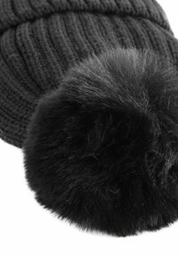 Berretto di maglia nera con design a coste, dotato di un grande pompon in pelliccia sintetica nera sulla sommità, che aggiunge texture e dettagli al cappello.
