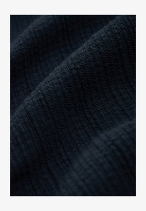 Dunkel marineblaue, strukturierte Stoff mit einem Gittermuster. Das Material wirkt gewebt, mit einer weichen und leicht erhabenen Oberfläche.