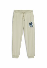 Lichtbeige sweatpants met elastische tailleband en sluitingen, met een blauw grafisch logo op de linker bovenbeen. Glad stoftextuur.