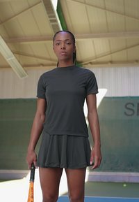 Conjunto deportivo gris que consiste en una camiseta ajustada de manga corta y una falda acampanada, hecha de material ligero, con una textura suave y sin patrones visibles.