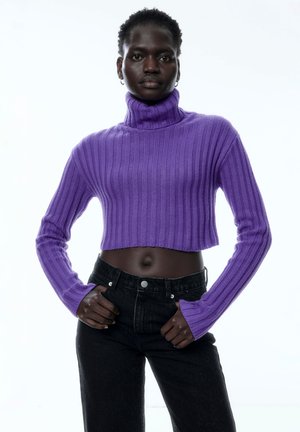 Lila gerippter Rollkragenpullover mit langen Ärmeln, cropped Design, getragen mit hochtaillierten schwarzen Jeans, betont Textur und Passform.