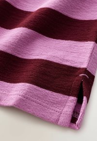 Tessuto rigato in tonalità di rosa e bordeaux, trama testurizzata, con orlo visibile e piccola fessura laterale all'orlo inferiore.