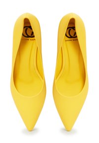 Los tacones de punta amarillos presentan un acabado liso y mate con un suave forro interior y un sutil logo en el interior del zapato.