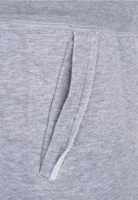 Šedé tepláky z měkké, texturované látky, s páskem na stažení a bočními kapsami pro praktičnost.