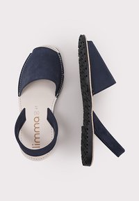 Marineblaue Wildleder-Absatzsandalen mit offener Rückseite und breitem Riemen. Ausgestattet mit einer strukturierten schwarzer Gummisohle und einem schlichten Design.