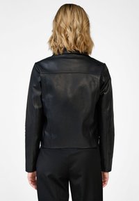 Black leather jacket with a fitted design, smooth texture, and tailored shoulders, featuring a zip closure and minimalistic tailoring.