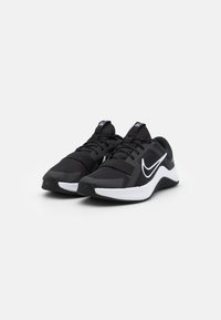 Zapatillas deportivas negras con parte superior de malla, acentos blancos y suela acolchada. Presentan un diseño clásico de cordones y el logo de Nike en el costado.