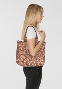 Gequiltte draagtas in luipaardprint, met een zachte, roze-bruinachtige stof en twee stevige hengsels. Zijaanzicht toont het ruime ontwerp en de textuur.