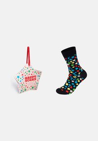 Calzini a stelle colorate su uno sfondo nero accanto a una scatola regalo a forma di stella con base bianca e dettagli rossi, contrassegnata con "HAPPY SOCKS."