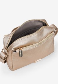 Bolso bandolera metálico dorado con un acabado texturizado, dos compartimentos con cremallera y una correa desmontable. Presenta una etiqueta de logo y un forro suave.