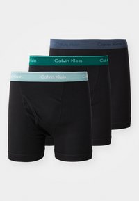 Drei Paar schwarze Boxershorts mit elastischen Taillengummis in Grau, Teal und Grün, mit dem "Calvin Klein"-Logo in kontrastierenden Farben.