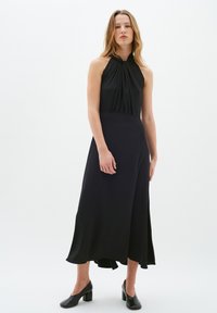 Rochie neagră cu gât halter, realizată dintr-o �țesătură moale, având un corset ajustat și o fustă fluidă cu o margine înaltă și joasă.