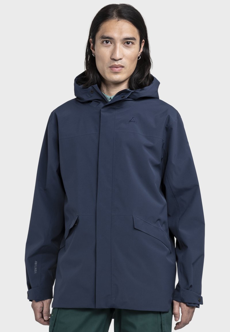 Marineblaue wasserdichte Jacke mit Kapuze, ausgestattet mit einem Frontverschluss, zwei Seitentaschen und dezenter Markenkennzeichnung am linken Ärmel.