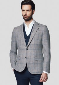 Szary marynarka w kratę z jasnoniebieskimi liniami, z dwoma przednimi guzikami i klapami, nałożona na granatową kamizelkę i białą koszulę.