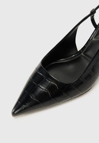 Zapato negro de tacón abierto con puntera afilada, confeccionado en cuero texturizado con patrón de cocodrilo, que presenta un diseño elegante y un interior negro liso.