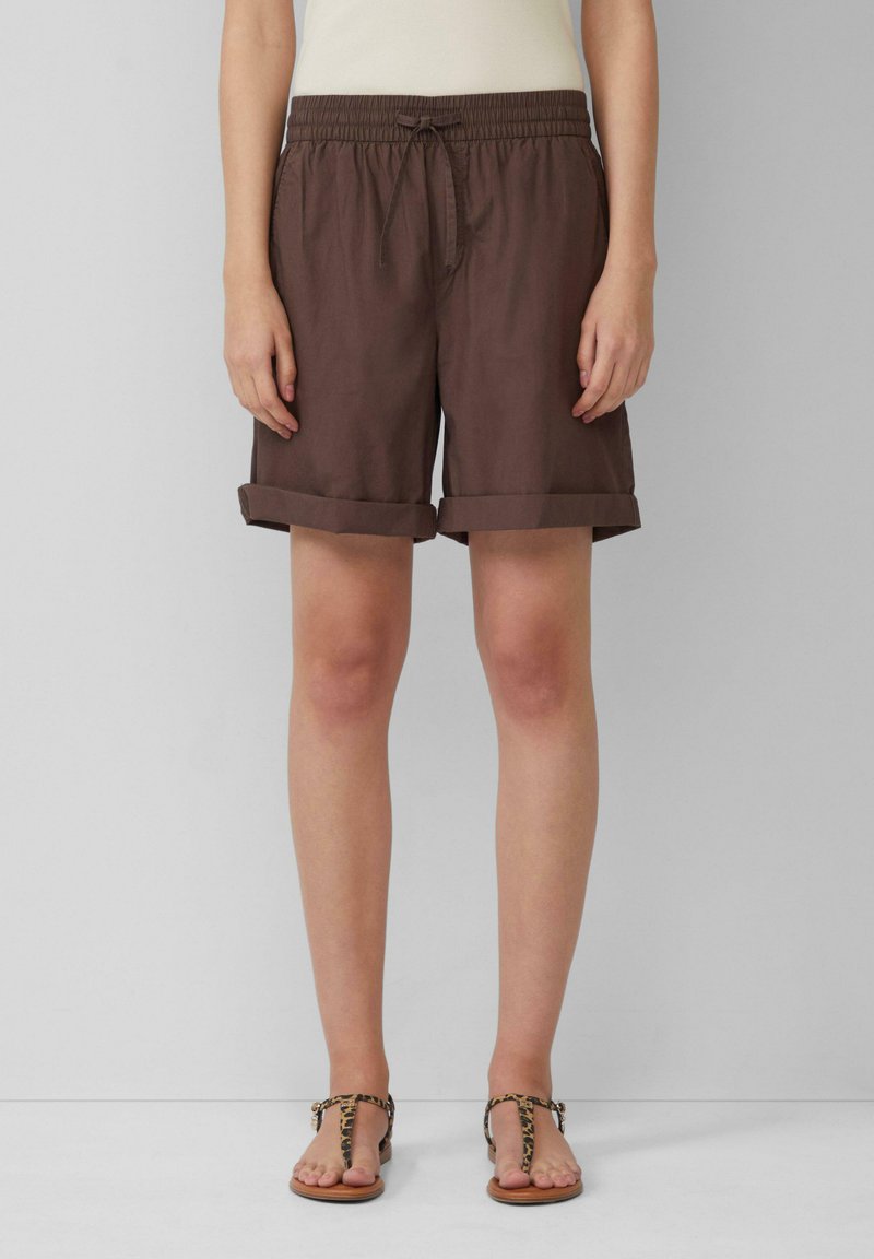 Bruine, middellange shorts met een elastische tailleband en een trekkoord. Omgeslagen zomen en lichtgewicht stof. Gecombineerd met sandaal in luipaardprint.
