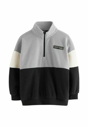Fleece pullover med høj krave, der har grå, cremefarvet og sort farveblokke, halv lynlås foran og et mærke syet på brystet.