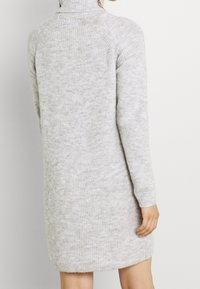 Light grey knitted sweater dress with a high collar, long sleeves, and a relaxed fit. Textured fabric with subtle color variation.