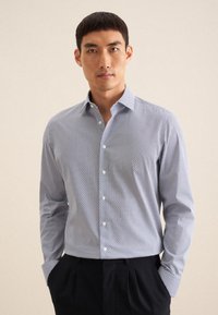 Lichtblauw button-up shirt met geometrisch patroon. Lange mouwen, gespreid kraag en een gladde, gestructureerde stof. Gecombineerd met donkere broeken.