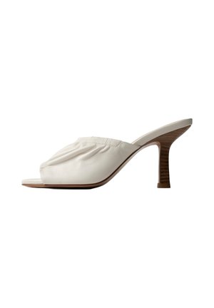 Witte open-toe mule met gerimpeld leren bovendeel en gebogen houten naaldhak, zijaanzicht op een witte achtergrond.