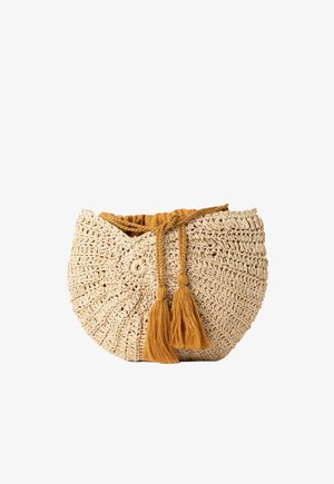 Sac à main rond tissé beige avec doublure en tissu marron et deux pompons marron suspendus à la fermeture à cordon tressé.