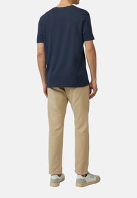 Navyblauwe katoenen t-shirt met korte mouwen, gecombineerd met lichtbeige chinos en witte sneakers. Eenvoudig ontwerp, casual pasvorm.