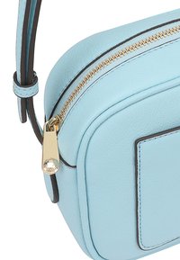 Lichtblauwe leren schoudertas met een ronde vorm, gouden ritsdetails en contrasterende bruine afwerking. Soepele textuur en minimalistisch ontwerp.