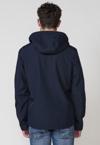 Chaqueta con capucha de color azul marino con una textura suave, que presenta una costura contrastante en la parte superior de la espalda y un diseño casual.