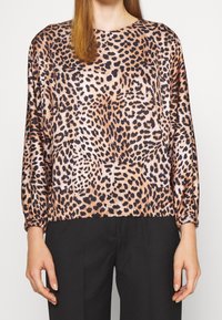 Top de estampado de leopardo con mangas largas, puños elásticos y escote redondo; presenta un acabado brillante en tonos marrón cálido y negro.