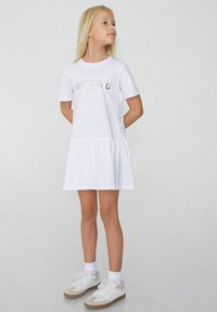 Weißes Baumwollkleid mit kurzen Ärmeln, einem ausgestellten Saum und dem Wort "SPARKLING" in metallischen Buchstaben auf der Vorderseite bedruckt. Einfache Textur.