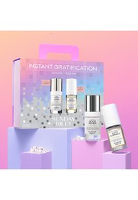 Ensemble de soins de la peau dans une boîte colorée, comprenant deux flacons en verre : un blanc avec un capuchon argenté, un autre transparent avec une étiquette aux accents dorés.