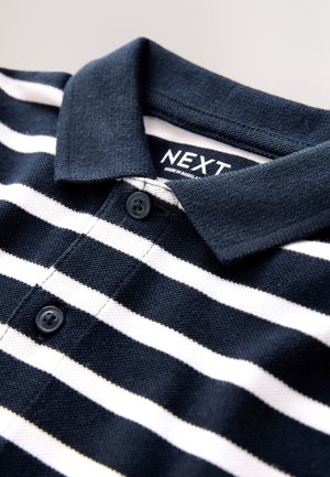 Tamsiai mėlynas polo marškinėlis su horizontaliomis baltomis juostelėmis, struktūruoto audinio, susegamas apykaklės kaklaraištis, viduje yra „NEXT“ etiketė. Dvi juodos sagos ant užtrauktuko.