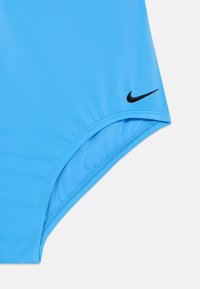 Blå Nike badedrakt med et strømlinjeformet design, glatte tekstiler og buede sømmer, med en liten svart logoakcent nær siden.