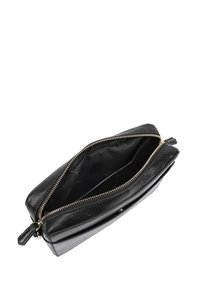 Zwarte leren clutch met een gladde textuur, gouden ritssluiting en een ongevoerde binnenkant. Heeft een platte vorm en een ritscompartiment.